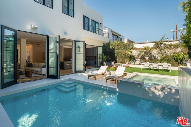 back of house with a patio area, a balcony, and a pool with hot tub