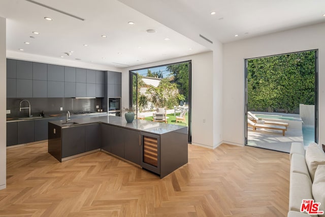 kitchen with backsplash, light parquet floors, beverage cooler, and sink