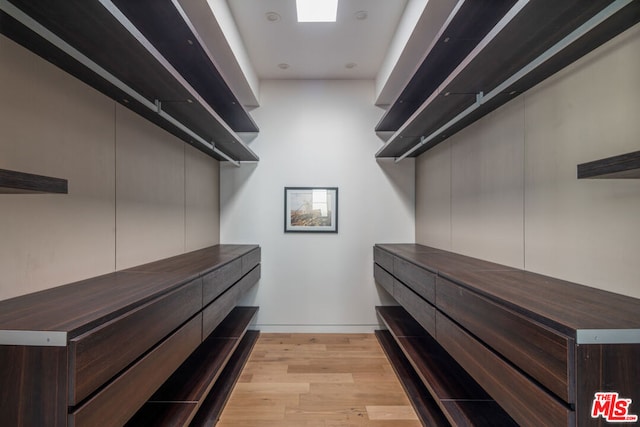 walk in closet with light hardwood / wood-style floors