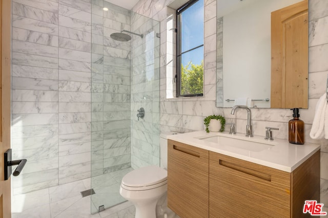 bathroom featuring vanity, decorative backsplash, toilet, tiled shower, and tile walls