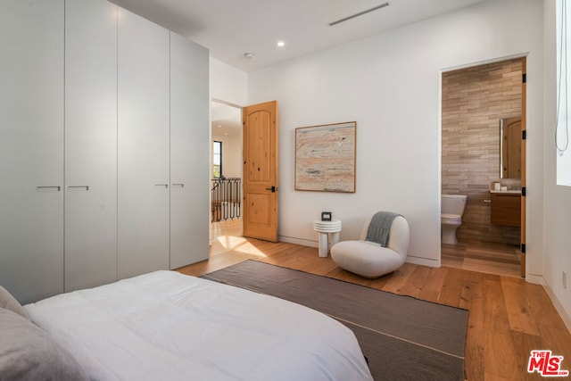 bedroom featuring light wood-type flooring, a closet, and connected bathroom