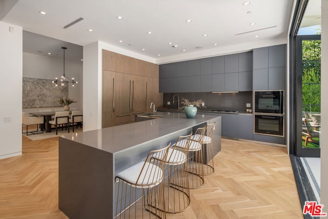 kitchen featuring a large island, hanging light fixtures, a kitchen breakfast bar, light parquet floors, and decorative backsplash