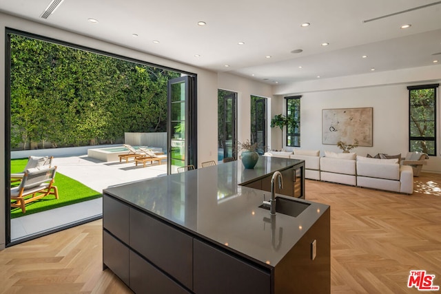 kitchen featuring a large island, sink, light parquet floors, and plenty of natural light