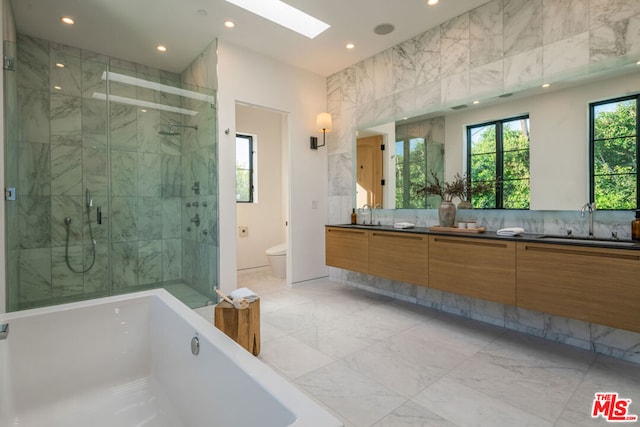 full bathroom with vanity, separate shower and tub, toilet, and a skylight