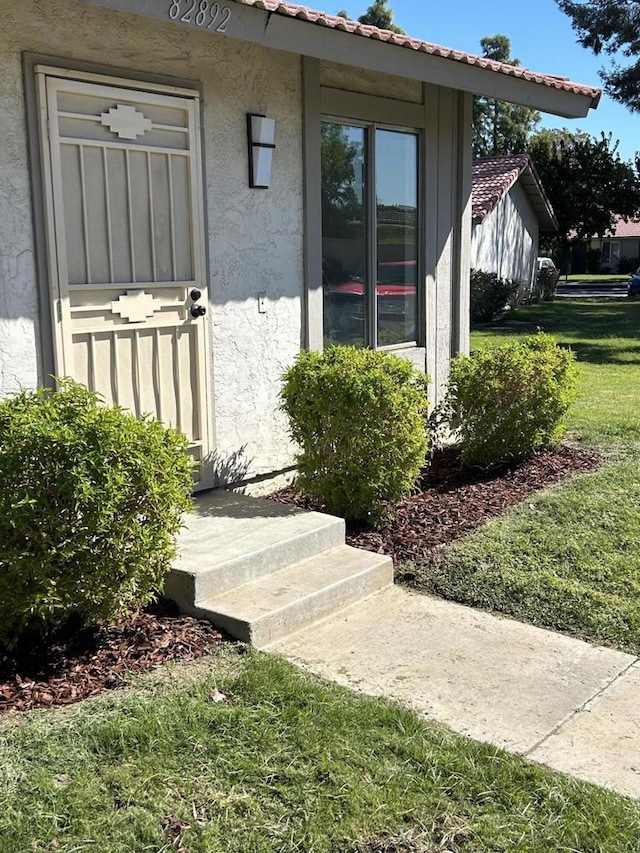 view of exterior entry with a yard