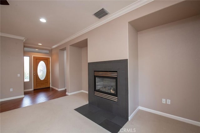 carpeted foyer with a tiled fireplace and ornamental molding