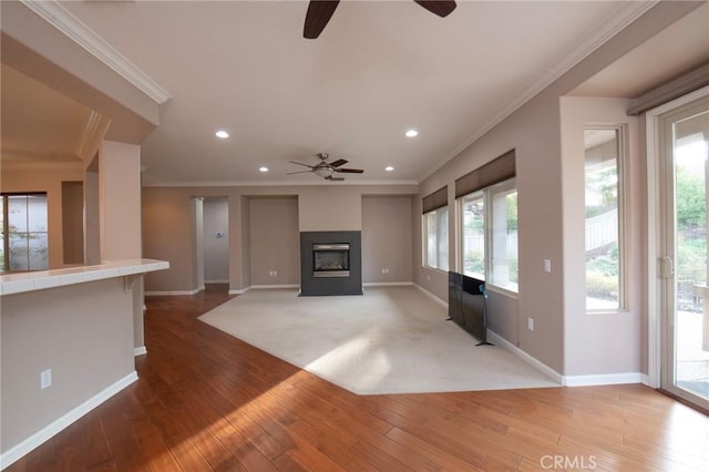 unfurnished living room with hardwood / wood-style floors, ceiling fan, and crown molding