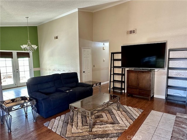 living room featuring french doors, dark hardwood / wood-style flooring, a textured ceiling, crown molding, and a notable chandelier