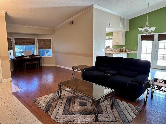 living room with crown molding, light wood-type flooring, a textured ceiling, and an inviting chandelier