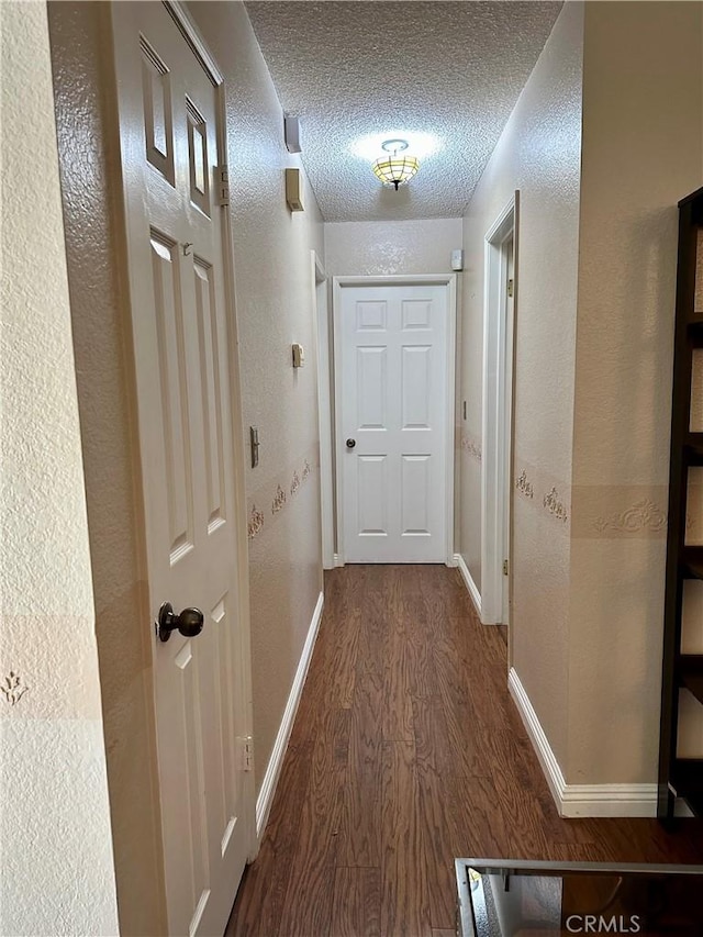 hall with dark hardwood / wood-style flooring and a textured ceiling