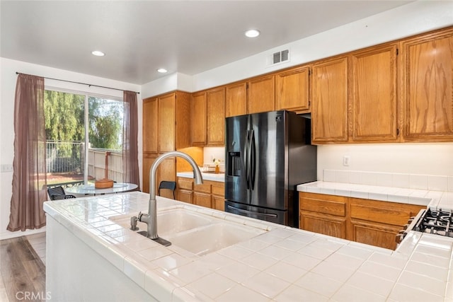 197 Lydia Ln, Corona, CA 92882 - kitchen with refrigerator with ice dispenser, tile counters, brown cabinets, a sink, and recessed lighting