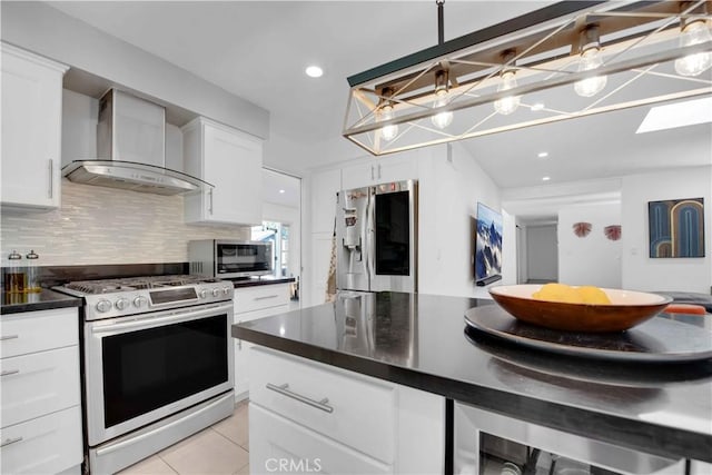 kitchen featuring appliances with stainless steel finishes, light tile patterned floors, white cabinetry, and wall chimney exhaust hood