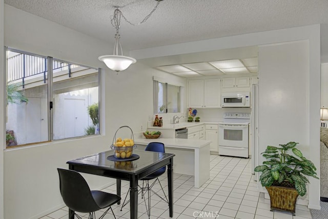 kitchen featuring white appliances, white cabinets, hanging light fixtures, light tile patterned floors, and a textured ceiling