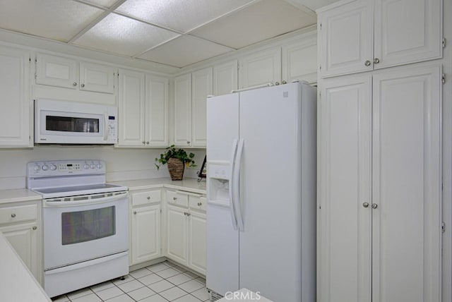 kitchen with white cabinets, a drop ceiling, light tile patterned flooring, and white appliances