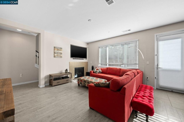 living room featuring hardwood / wood-style flooring, a healthy amount of sunlight, and a tile fireplace