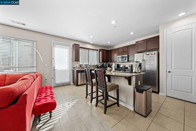 kitchen with plenty of natural light, a center island, stainless steel appliances, and a breakfast bar area