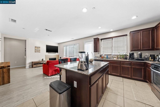 kitchen featuring light hardwood / wood-style flooring, a kitchen island, a wealth of natural light, and stainless steel range with electric cooktop