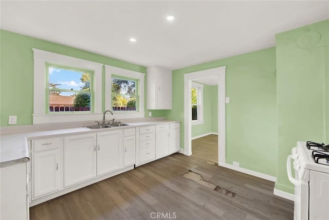 kitchen featuring hardwood / wood-style floors, white range oven, white cabinetry, and sink