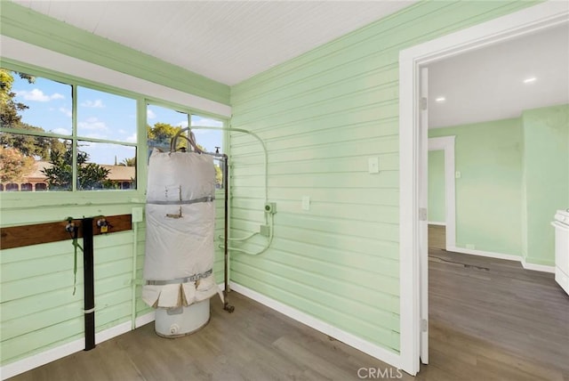 bathroom with hardwood / wood-style floors, wood walls, and water heater