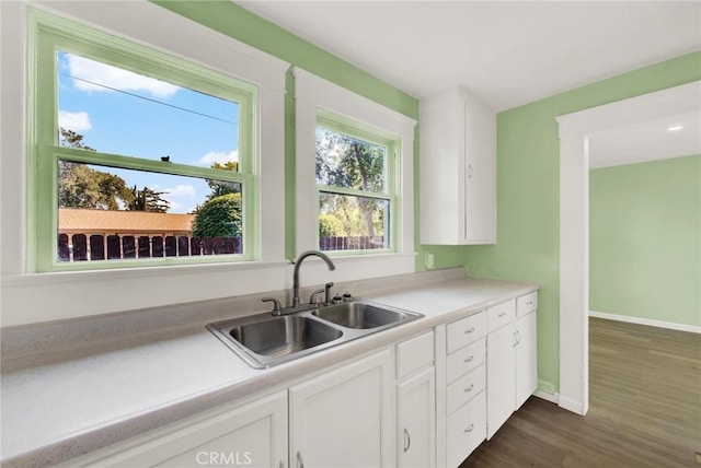 kitchen with dark hardwood / wood-style flooring, white cabinetry, and sink