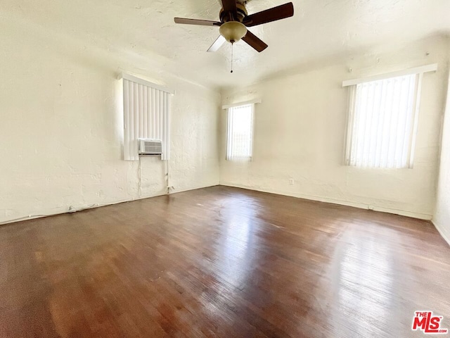 empty room featuring ceiling fan, cooling unit, and dark hardwood / wood-style floors