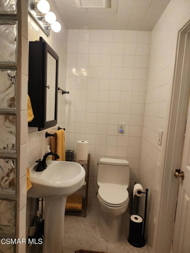 bathroom with decorative backsplash, tile walls, toilet, and tile patterned floors