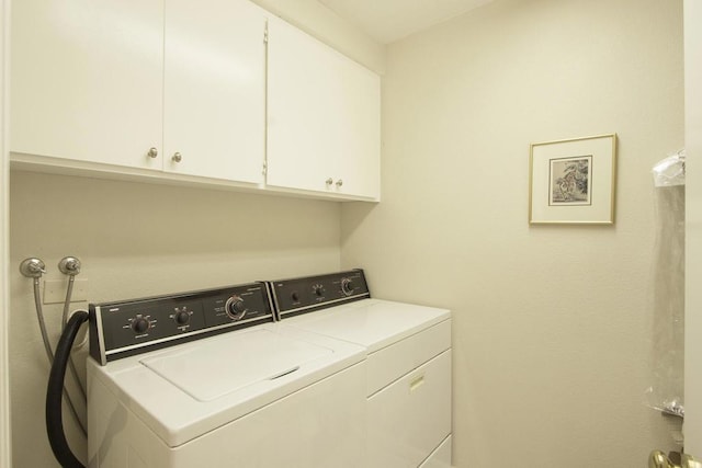 clothes washing area with washer and dryer and cabinets