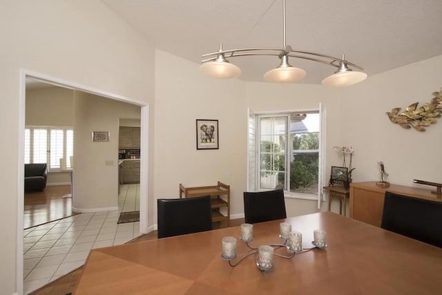 tiled dining room featuring plenty of natural light and vaulted ceiling