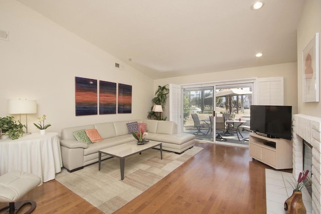 living room with hardwood / wood-style flooring, a fireplace, and vaulted ceiling