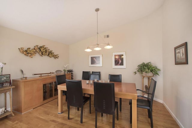 dining room featuring light wood-type flooring and vaulted ceiling