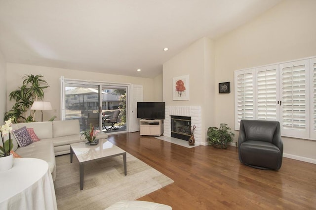 living room with hardwood / wood-style floors, a fireplace, and vaulted ceiling