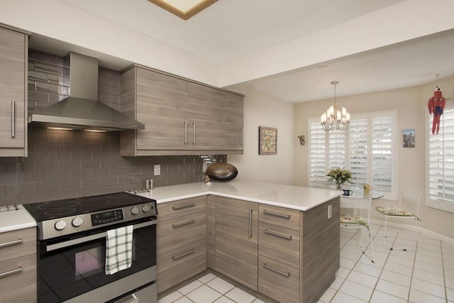 kitchen featuring an inviting chandelier, electric stove, wall chimney exhaust hood, tasteful backsplash, and kitchen peninsula