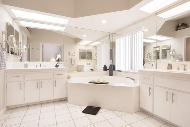 bathroom with tile patterned floors, tiled bath, and vanity