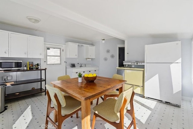 dining space featuring beam ceiling and sink