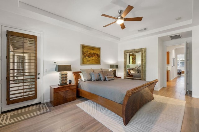 bedroom featuring access to outside, a raised ceiling, ceiling fan, and light hardwood / wood-style flooring