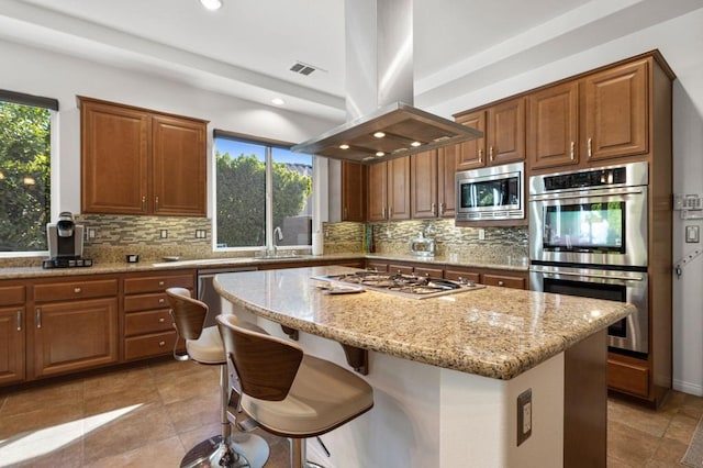 kitchen with a healthy amount of sunlight, island range hood, a center island, and stainless steel appliances