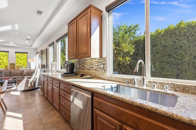 kitchen featuring light stone countertops, sink, stainless steel dishwasher, decorative backsplash, and light tile patterned flooring