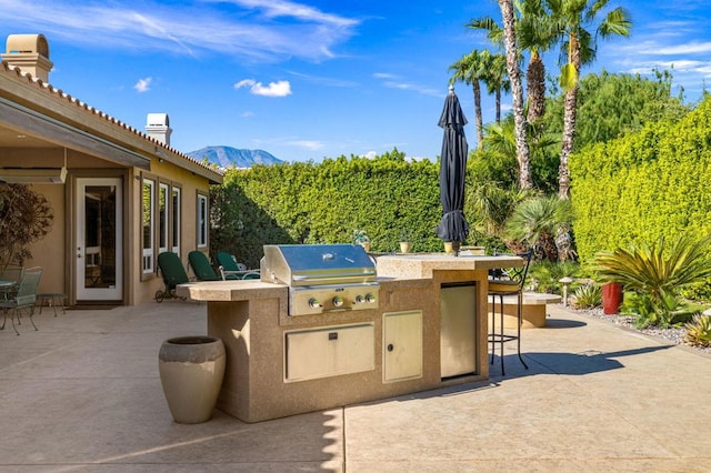 view of patio with a mountain view, area for grilling, and an outdoor bar