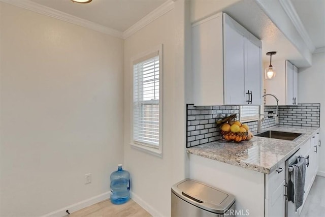 kitchen with hanging light fixtures, light stone counters, sink, white cabinetry, and tasteful backsplash