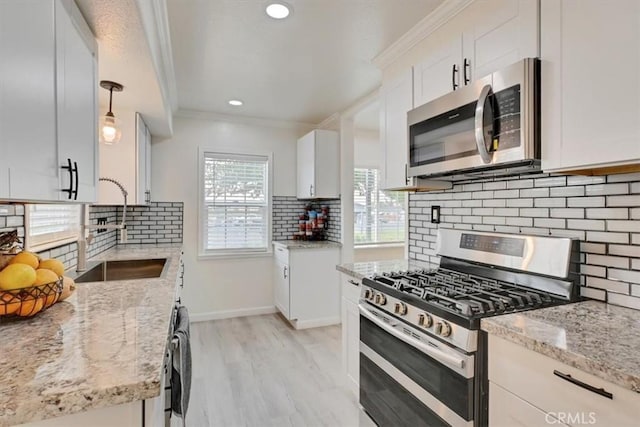 kitchen featuring sink, white cabinetry, light stone countertops, pendant lighting, and appliances with stainless steel finishes