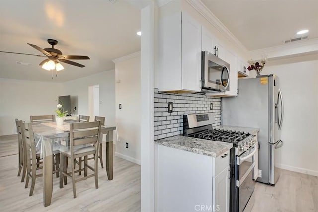 kitchen with light stone counters, stainless steel appliances, light hardwood / wood-style floors, white cabinetry, and ceiling fan