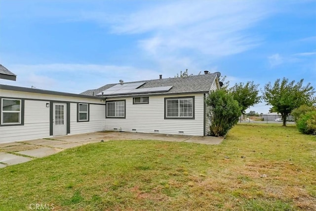 rear view of property featuring a lawn, solar panels, and a patio area