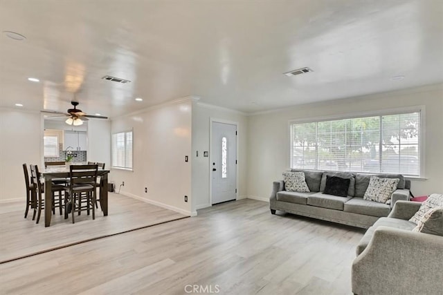 living room with ceiling fan, crown molding, and light wood-type flooring