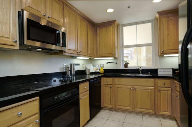 kitchen with sink, light tile patterned floors, black appliances, and dark stone counters