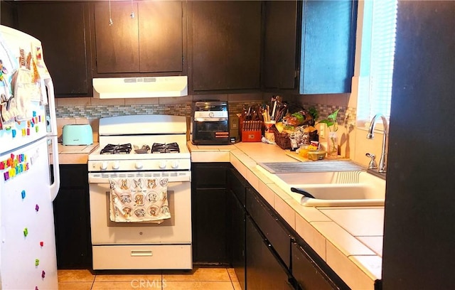 kitchen with white appliances, sink, light tile patterned floors, tasteful backsplash, and dark brown cabinets