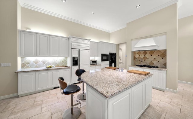 kitchen with tasteful backsplash, white cabinets, and an island with sink