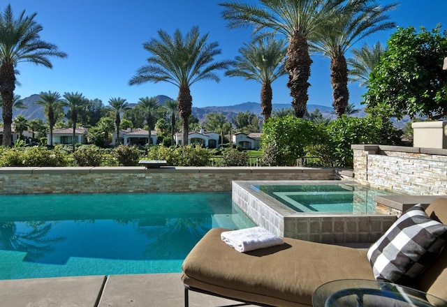 view of swimming pool with a mountain view and an in ground hot tub