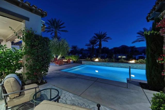 pool at night with a patio area