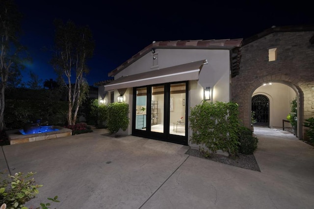 exterior entry at twilight featuring french doors and a patio area