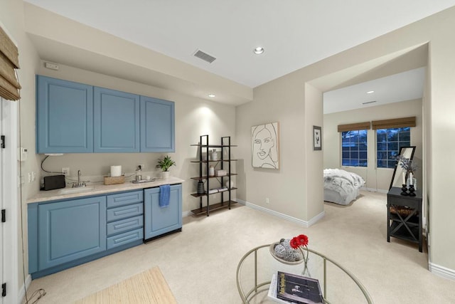 interior space with blue cabinetry, sink, and light carpet